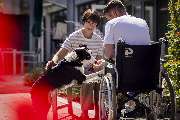 Augustinus Hospiz - St. Augustinus Gruppe - Ein Mann im Rollstuhl, eine Frau und ein Hund im Garten des Hospizes. Der Hund legt seine Pfote in die Hand des Mannes – ein liebevoller Moment, der Nähe und Lebensfreude ausdrückt.