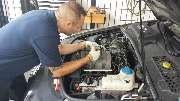 Auto Service Friesdorf I Kfz-Werkstatt I Reifenhandel - Mitarbeiter arbeitet an geöffneter Motorhaube