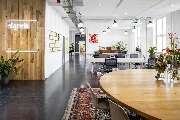 Bande für Gestaltung - Modernes, lichtdurchflutetes Büro mit offenen Arbeitsbereichen, Holzelementen und stilvoller Inneneinrichtung. Das „signals“-Neonlogo an der Wand steht für Innovation und kreative Zusammenarbeit.