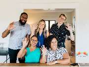 Bifröst InmoPro – Marketing für Immobilienmakler - The Bifröst InmoPro team welcomes you with a smile! A diverse and cheerful group waves at the camera, representing approachability, customer care, and collaborative spirit. This image reflects Bifröst’s m