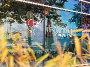 Das Blümchen | Restaurant Friedrichshafen - Außenansicht des Restaurants Das Blümchen Friedrichshafen mit Logo und Schriftzug „Schwarzwald Tapas“ auf der Glasfassade – moderne Architektur mit Seespiegelung.