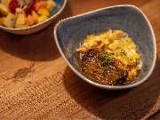 Das Blümchen | Restaurant Friedrichshafen - Tapasgericht mit Fleisch und Sauce auf Holzbrett mit Logo Das Blümchen Schwarzwald Tapas.