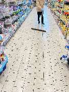 E&E Gebäudereinigung - E&E Gebäudereinigung Gründliche Bodenreinigung in einem Supermarktgang, bei der eine Fachkraft mit Besen lose Verschmutzungen auf hellen Fliesen entfernt, um ein sauberes und gepflegtes Einkaufserlebnis zu gewährleisten.