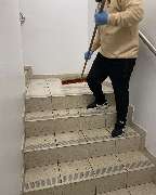 E&E Gebäudereinigung - E&E Gebäudereinigung Gründliche Treppenreinigung, bei der eine Fachkraft mit Besen losen Schmutz und Ablagerungen entfernt, um ein sauberes und sicheres Treppenhaus zu gewährleisten.