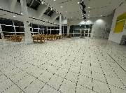 E&E Gebäudereinigung - E&E Gebäudereinigung Weiträumige Halle mit sauberem, frisch gereinigtem Fliesenboden und ordentlich angeordneten Tischen, die ein gepflegtes und einladendes Gesamtbild vermittelt.