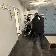 Fein Gebäude-Service - Zwei Mitarbeiter reinigen einen Umkleidebereich mit Spinden und Waschraumzugang, ausgestattet mit professionellem Reinigungswagen.