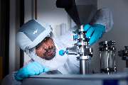 Foto und Filmproduktion Laila Tkotz - Foto und Filmproduktion Laila Tkotz Forscher im Reinraum prüft industrielle Laboranlage mit Schutzanzug und Handschuhen