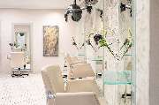 Friseur HAARSCHARF natürlich & schön Chemnitz Spezialisten für Extensions und Farbtechniken, Brautstyling - Das Bild zeigt einen eleganten und modern eingerichteten Friseursalon mit einer Reihe von stilvollen Frisierplätzen. Die hellen, beigen Friseurstüh