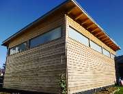 Hubert Bader Holzbau GmbH - Diese Doppelgarage besitzt eine Lärchen-Stülpschalung und auf der gegenüberliegenden Seite ein Sektionaltor.