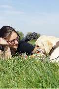 Hundeberatung für Familienhunde - Kluge Hunde - Ein Moment echter Verbindung: Eine Frau liegt entspannt mit ihrem Hund auf der Wiese. Gemeinsame Zeit, Vertrauen und spielerisches Miteinander – das ist die Basis für ein starkes Mensch-Hund-Team.