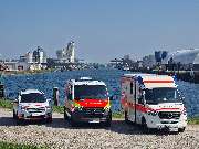 Johanniter-Unfall-Hilfe e.V. - Rettungswache Kehl - Drei Einsatzfahrzeuge der Johanniter in Kehl vor der Kulisse des Kehler Rheinhafens.