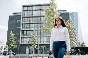 Julia Reisinger Fotografie - Julia Reisinger Fotografie Dynamisches Business-Porträt einer Frau in weißer Bluse vor urbaner Architektur.