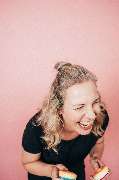 Julia Reisinger Fotografie - Julia Reisinger Fotografie Fröhliches Portrait einer Frau mit einem breiten Lächeln vor pastellfarbenem Hintergrund, ideal für positive und lebendige Bildsprache.
