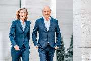 Julia Reisinger Fotografie - Julia Reisinger Fotografie Professionelles Businessfoto zweier Führungskräfte im Anzug, aufgenommen in urbaner Umgebung.