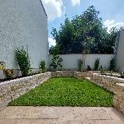 Kropp Gartenbau Schwetzingen - Naturstein-Terrasse mit angrenzendem Garten, junger Baum, Ziergräsern und Rollrasen – stilvolle, moderne Gartengestaltung.