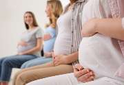 Mamagold | Pilates für Schwangere & Mamas - Das Bild zeigt vier schwangere Frauen, die entspannt nebeneinandersitzen und ihre Babybäuche halten. Diese Szene repräsentiert die Geburtsvorbereitungskurse bei Mamagold Stuttgart, die werdende Mütter umfassend 