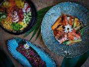 MAUI - Hawasian & Vietnamese Restaurant | München Ludwigpalais - Dreiteilige Food-Komposition aus Poké Bowl, Lachsgericht und Longplate mit Thunfischtatar – kunstvoll angerichtet auf tropischem Hintergrund.