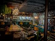 MAUI - Hawasian & Vietnamese Restaurant | München Ludwigpalais - Einladender Restaurantbereich mit rustikaler Decke, grünem Interior, stilvoll gedeckten Tischen und atmosphärischer Beleuchtung – modernes Ambiente mit Naturflair.