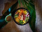 MAUI - Hawasian & Vietnamese Restaurant | München Ludwigpalais - Frische Poké Bowl mit Garnelen, Mango, Edamame, Avocado, Rotkohl und Karotten, serviert mit einem Dip auf tropischen Blättern angerichtet.