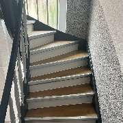 MC Bodenservice - Parkettleger & Bodenleger - Das Bild zeigt eine fachgerecht mit Laminat belegte Treppe. Die Stufen wurden passgenau verkleidet, inklusive sauberer Kantenbearbeitung und farblich abgestimmter Leisten – für ein harmonisches Gesamtbild.