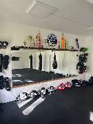 Muay Thai Kassel - dein Gym für authentisches Thaiboxen. - Muay Thai Kassel - dein Gym für authentisches Thaiboxen. Trainingsraum mit Pokalen und Equipment, der Professionalität und langjährige sportliche Erfolge widerspiegelt.