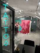 OMEN Tattoo & Piercing - Berlin Mitte - Empfangs- und Wartebereich im OMEN Tattoo Studio Berlin Mitte mit Galerie-Flair, heller Einrichtung und stilvollem Neon-Schriftzug.