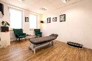 Physiotherapie Human-Health-Concepts - by Andreas Koch - Das Bild zeigt einen ruhigen Behandlungsraum mit einer Therapieliege und zwei Stühlen – funktional und klar eingerichtet.
