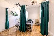 Physiotherapie Human-Health-Concepts - by Andreas Koch - Das Bild zeigt zwei geöffnete Behandlungskabinen mit Vorhängen und Einblick auf die Therapieliegen.
