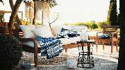 pietschpictures - Eine stilvoll eingerichtete Terrasse mit Holzmöbeln, Textilien in Blau-Weiß und mediterranen Details lädt zum Entspannen ein. Das warme Sonnenlicht und die natürliche Umgebung erzeugen ein Gefühl von Urlaub und Leichtigkeit.