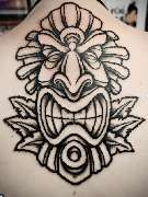 Schmierfink & Robird - Schmierfink & Robird kräftiges traditionelles tattoo einer stilisierten maske auf dem rücken, inspiriert von polynesischen und tribal elementen, mit starken linien und kontrastreicher schattierung