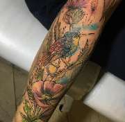 Schmierfink & Robird - Schmierfink & Robird lebendiges tattoo eines kolibris mit floralen elementen, farbenprächtiger aquarellstil kombiniert mit feiner linienarbeit für natürliche dynamik