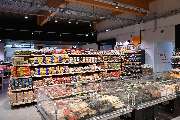 tegut... gute Lebensmittel - Innenansicht des tegut... Supermarktes mit verschiedenen Brotsorten im Vordergrund und Feinkost-Bedientheken im Hintergrund.