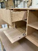 Tischlerei Hennemann - Tischlerei Hennemann Hochwertiges Möbelstück in Fertigung mit präzisen Schubladen und Klapptür. Demonstriert individuelle Möbelanfertigung, feine Holzverarbeitung und funktionale Innenausstattung.